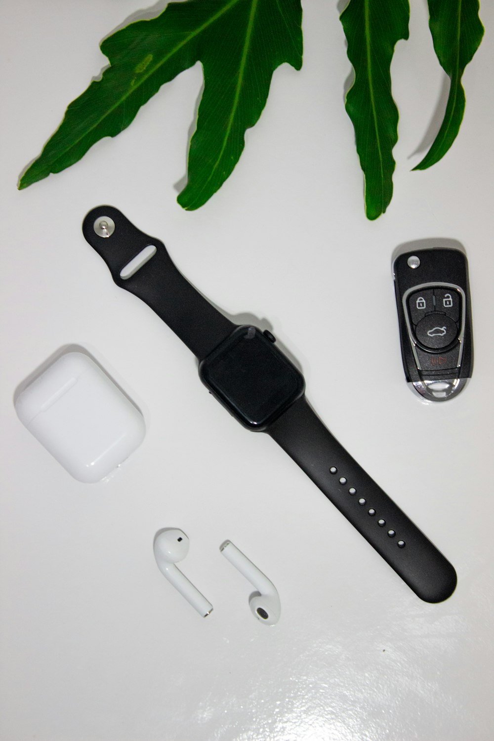 Mando a distancia negro y plateado junto al Apple Watch con correa deportiva negra