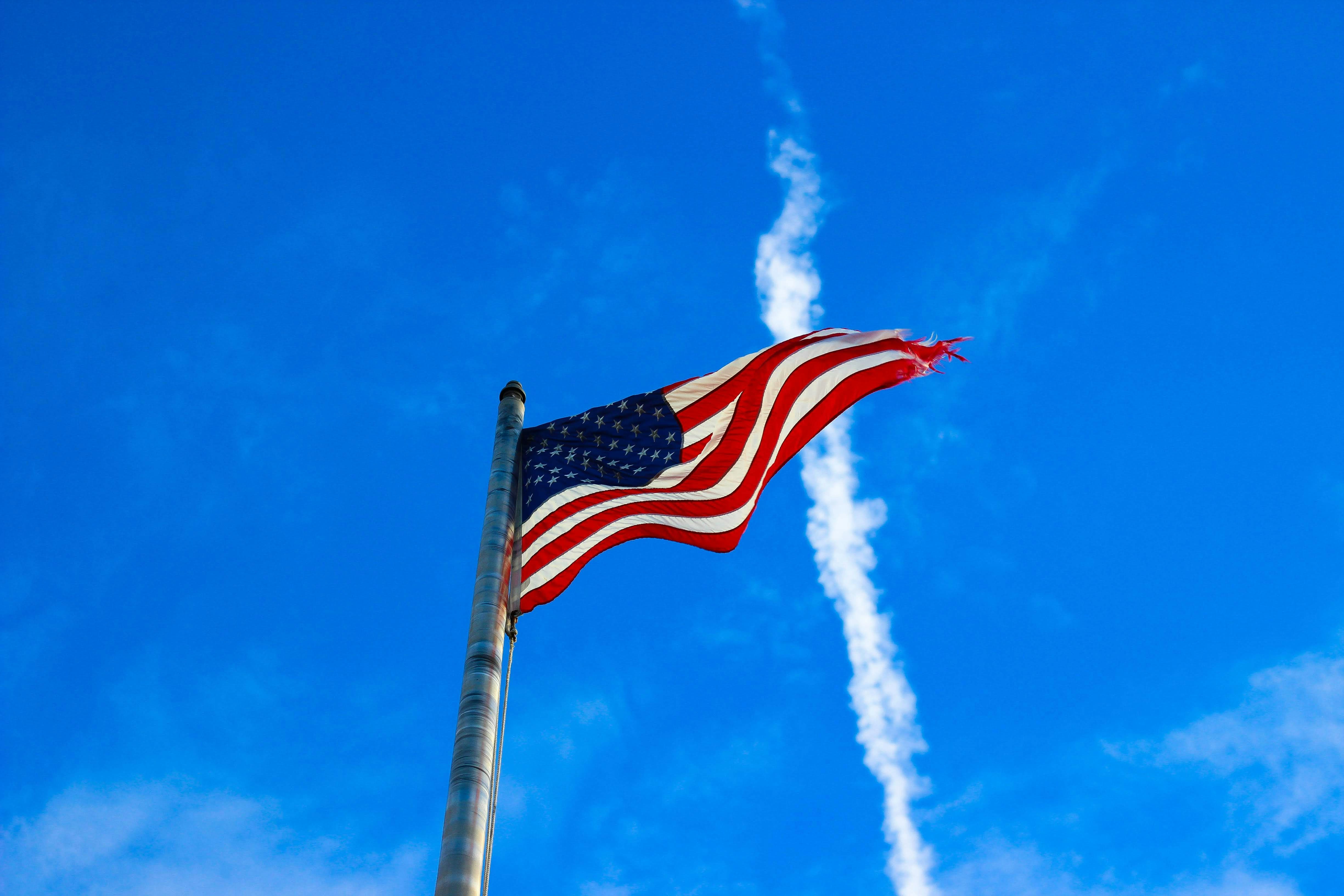 us a flag on pole under blue sky during daytime