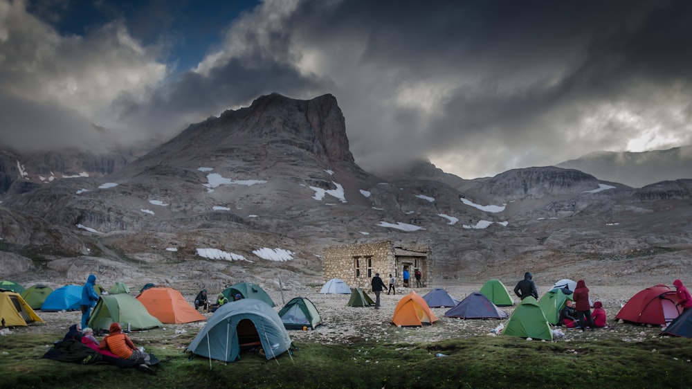 green tent near mountain under cloudy sky during daytime