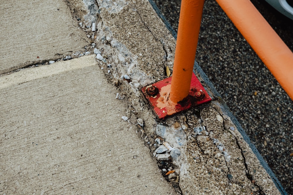 orange metal pipe on gray concrete pavement