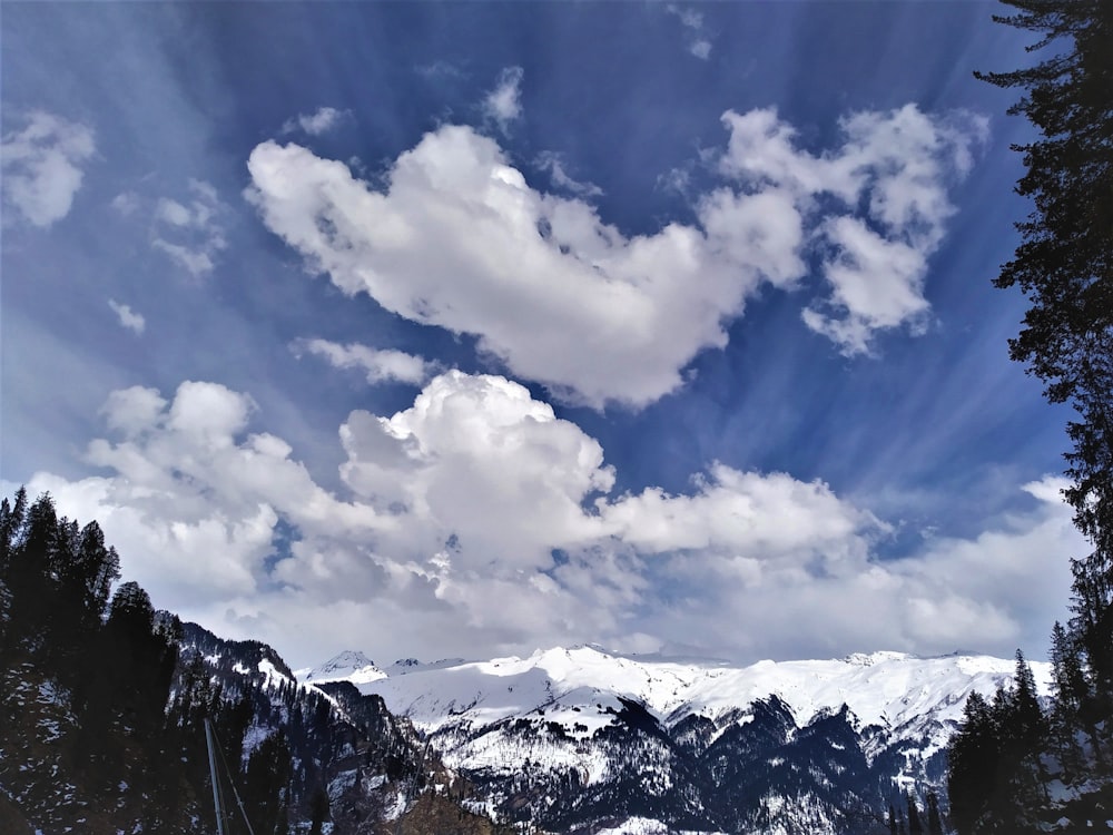 snow covered mountain under blue sky and white clouds during daytime