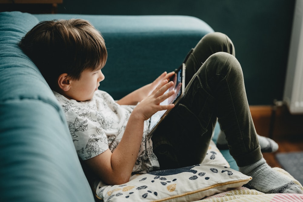 boy in white shirt and black pants sitting on couch