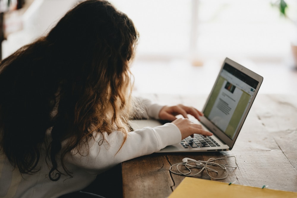 woman in white long sleeve shirt using macbook pro