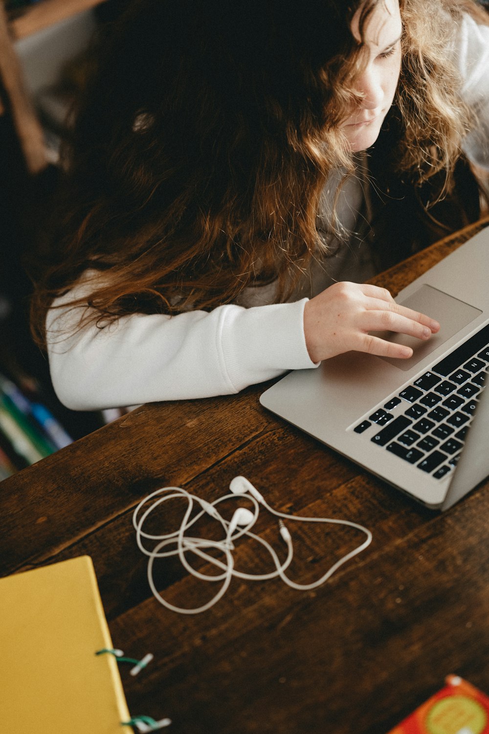 woman in white long sleeve shirt using macbook pro