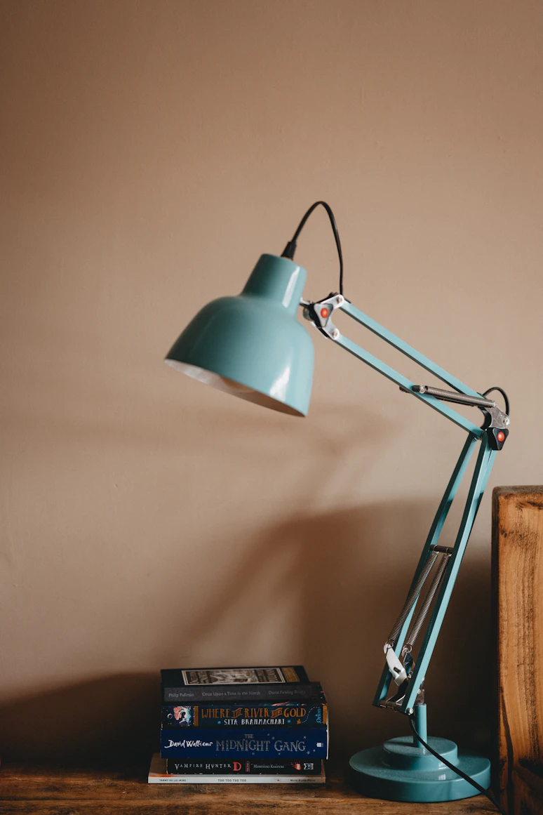 An Anglepoise reading lamp on a desk beside an open book