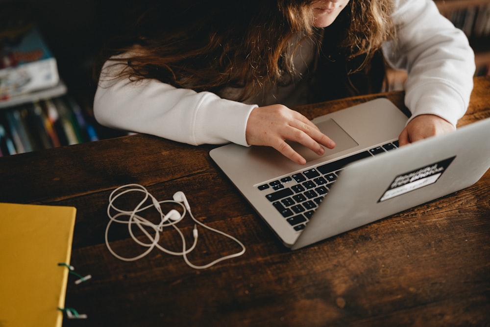 woman in white long sleeve shirt using macbook air