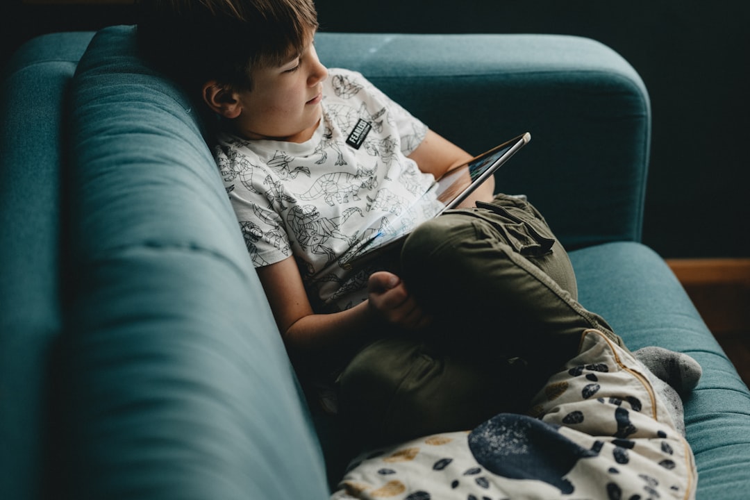 boy in white and black crew neck t-shirt and gray pants sitting on black couch
