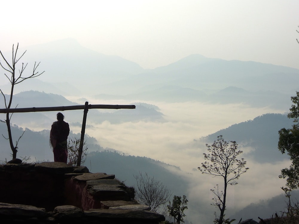 man in black jacket sitting on brown rock during daytime