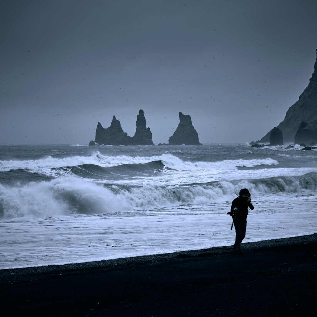 silhouette of person standing on seashore near ocean waves during daytime