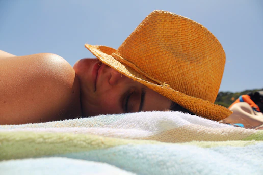 A man in a straw hat laying on a towel