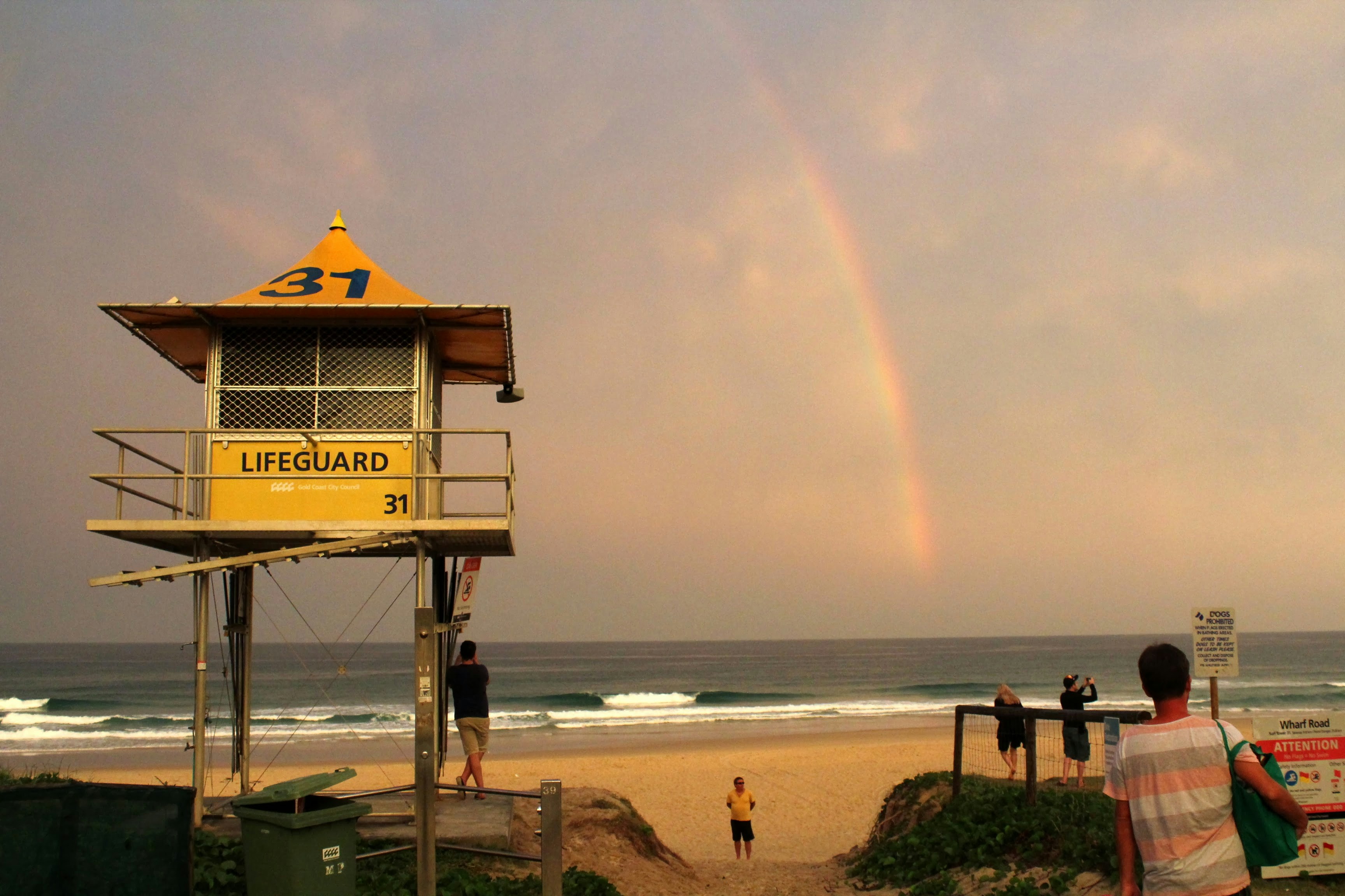 A rainbow appears over a lifeguard tower on a beach