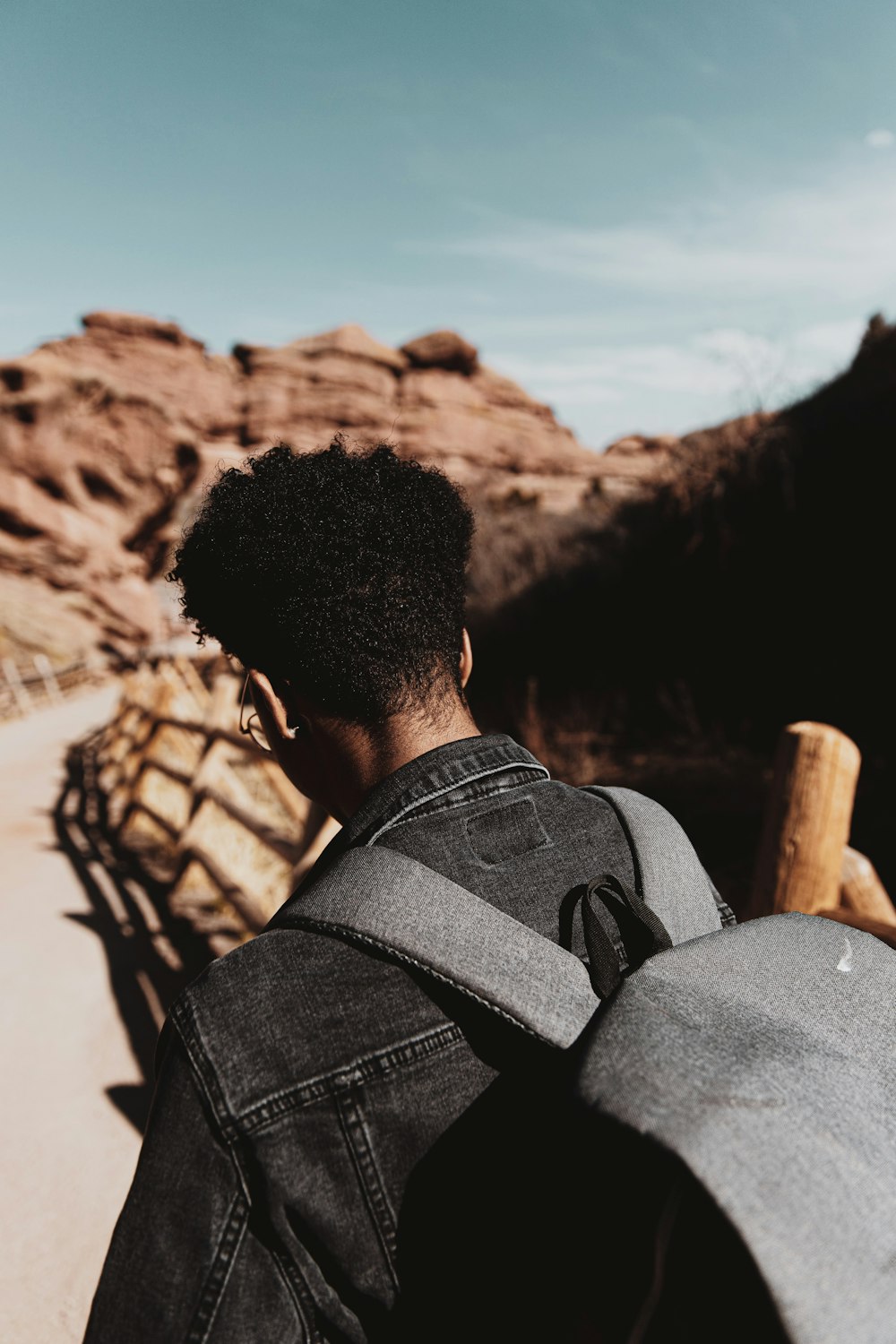 uomo in camicia nera in piedi vicino alla formazione rocciosa marrone durante il giorno