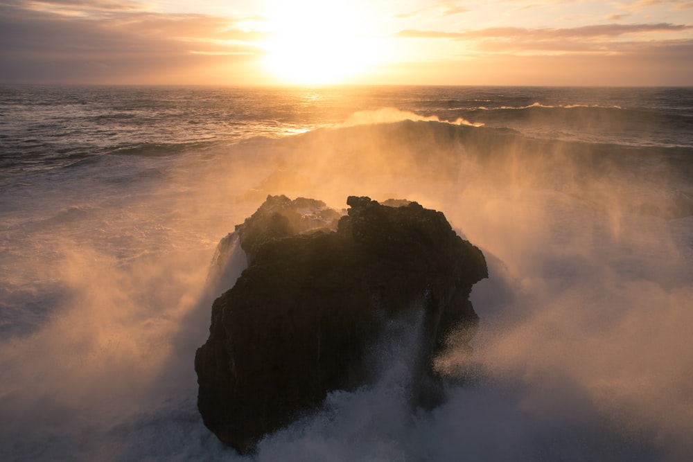 ocean waves crashing on black rock formation during daytime