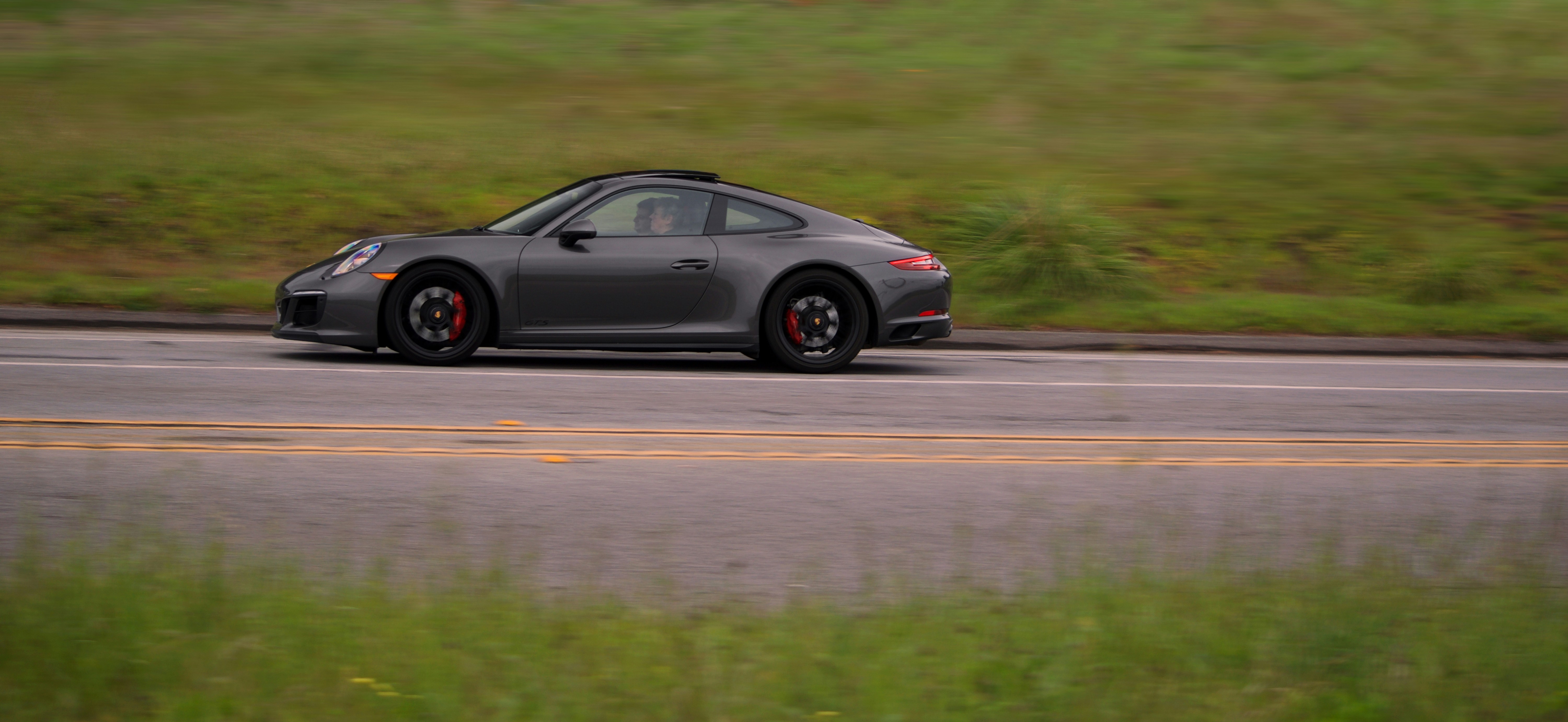 A gray Porsche driving on the highway.