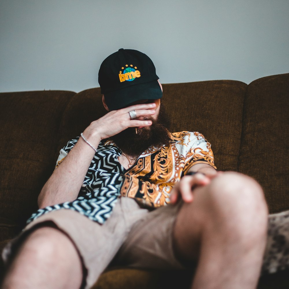person in black and orange cap and black and white shirt lying on brown sofa