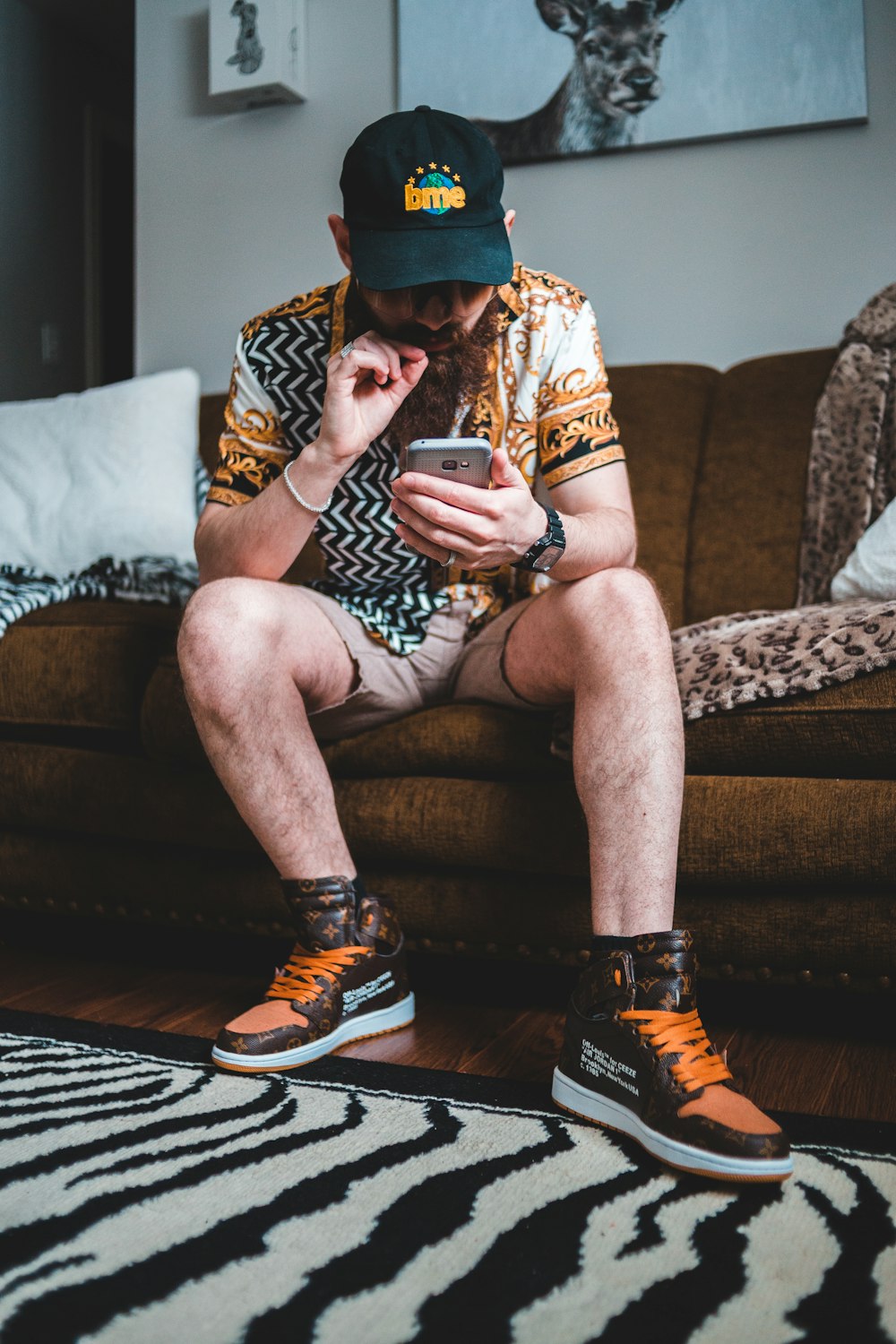 man in black and white tank top sitting on brown couch