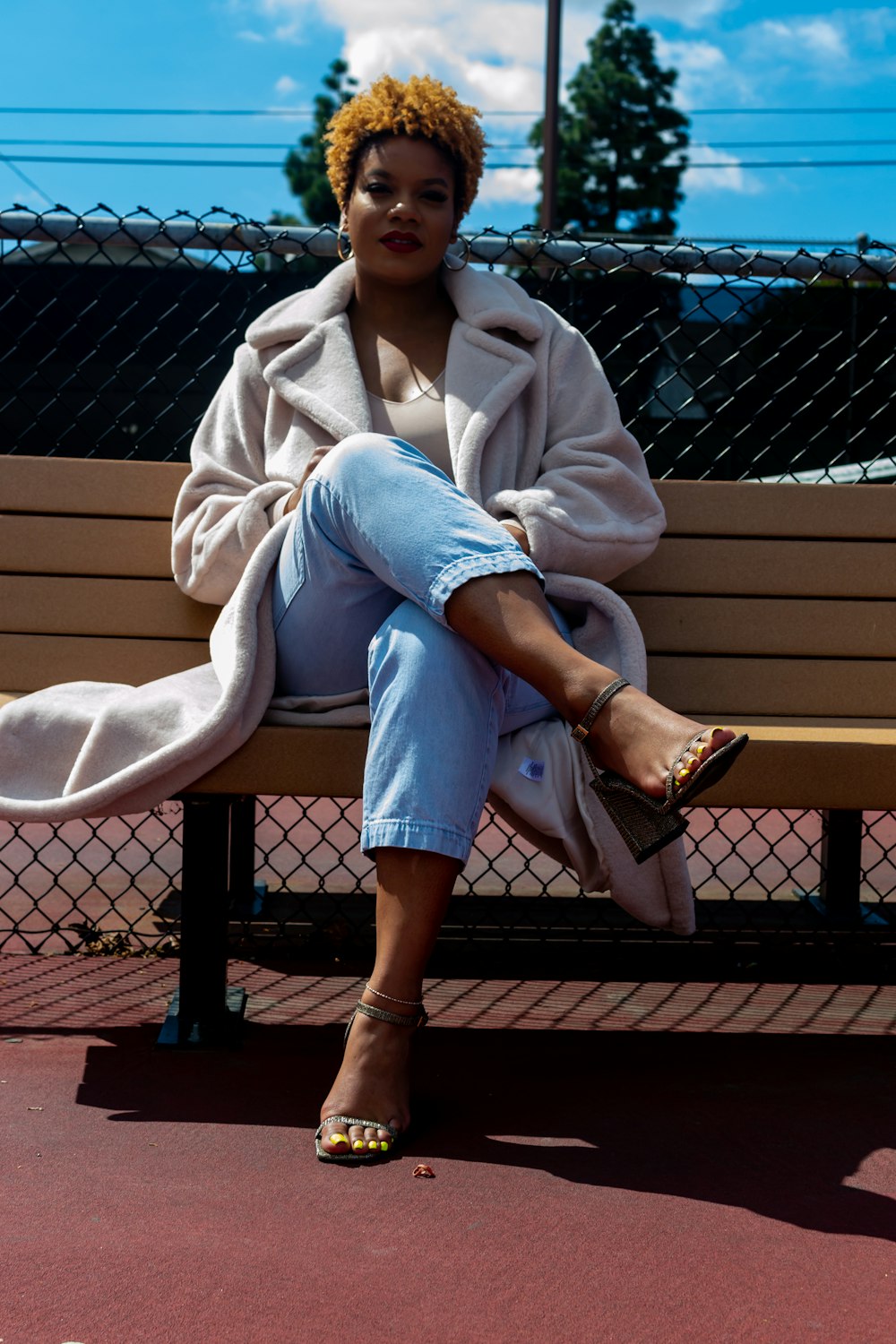 woman in white coat sitting on brown wooden bench