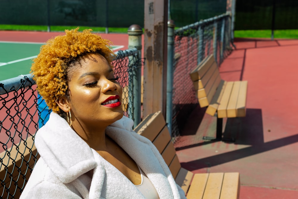 woman in white coat sitting on brown wooden bench