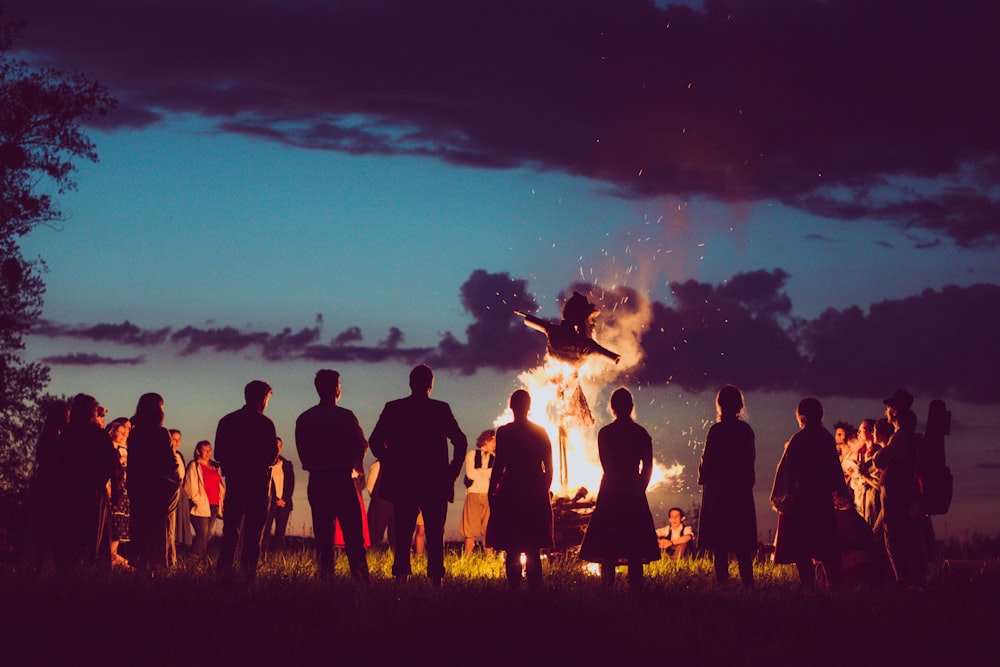 silhouette of people standing on grass field during sunset