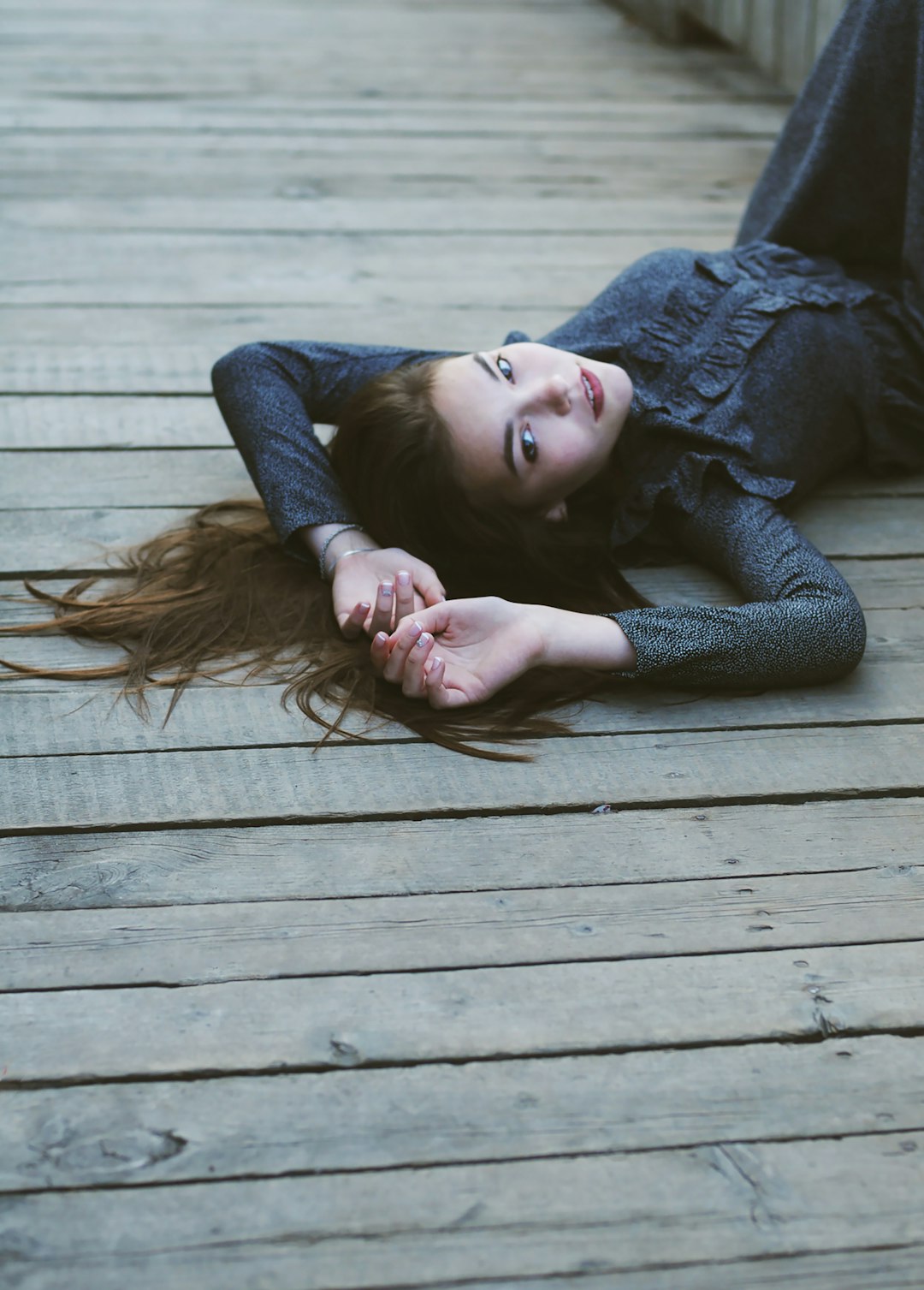 woman in blue denim jacket lying on brown wooden floor