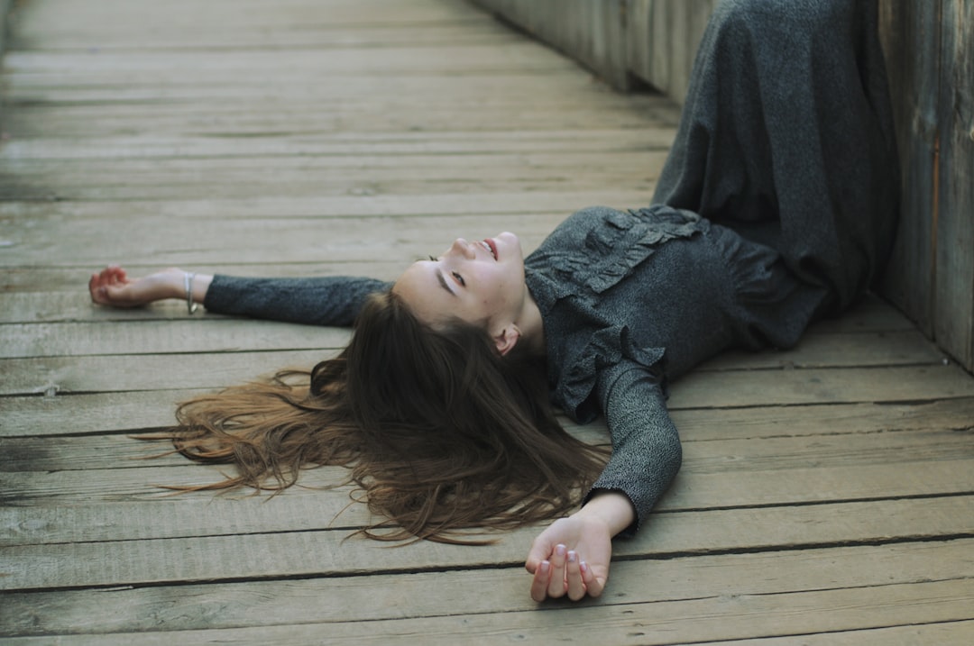 woman in gray sweater lying on brown wooden floor
