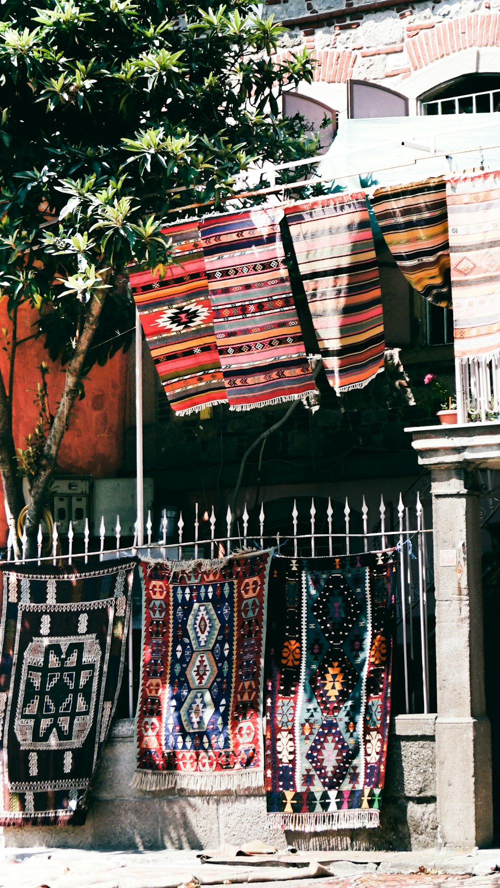 Textil de estampado tribal rojo, azul y blanco sobre valla metálica blanca