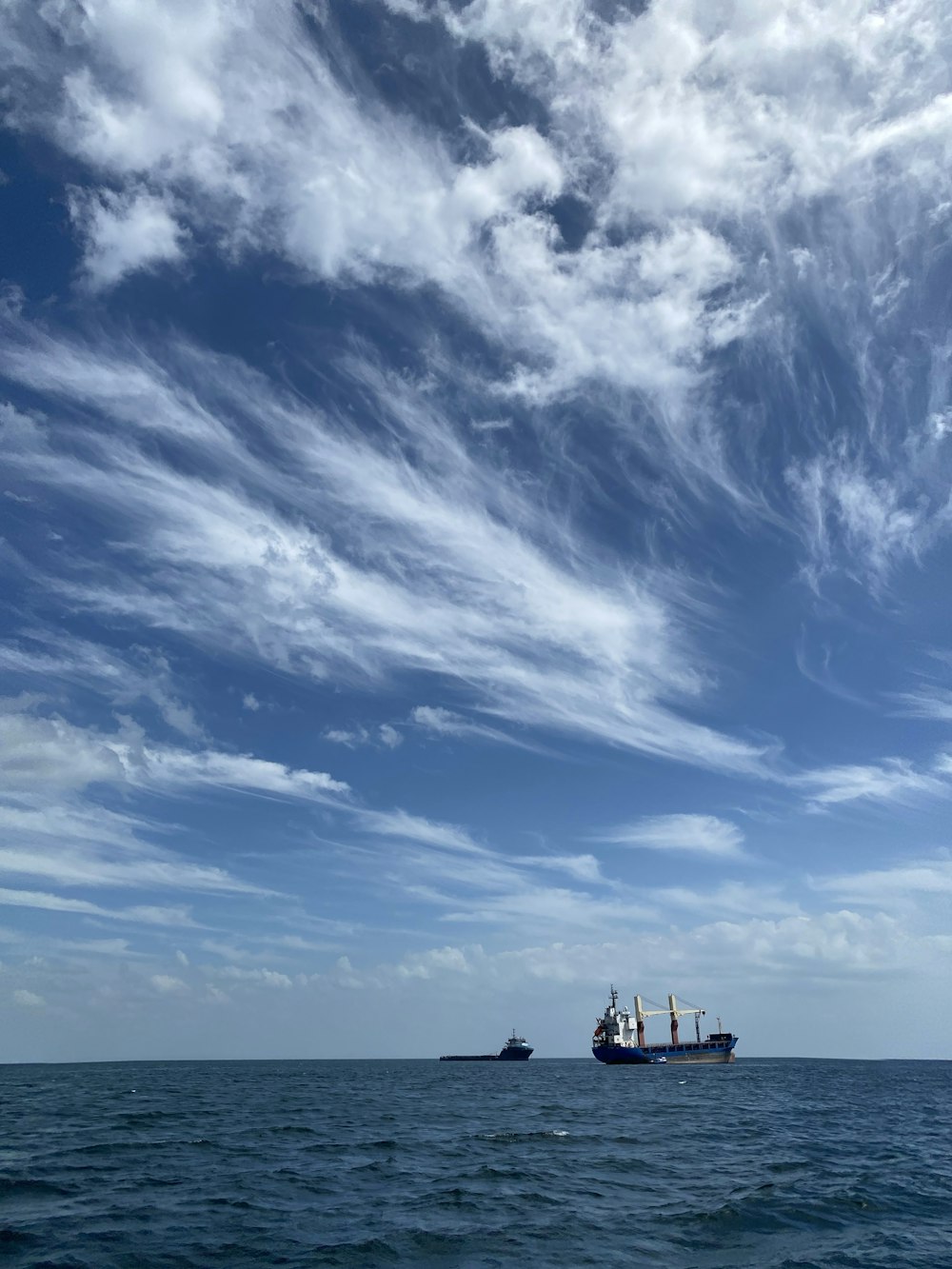 white boat on sea under blue sky and white clouds during daytime