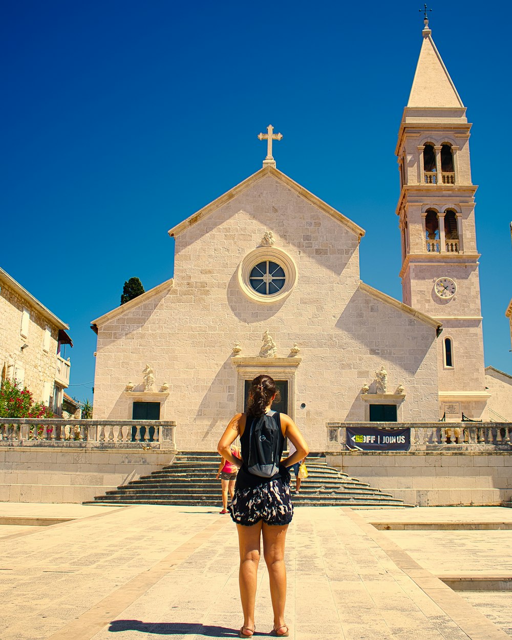 Donna in abito bianco e nero in piedi davanti alla chiesa di cemento bianco durante il giorno