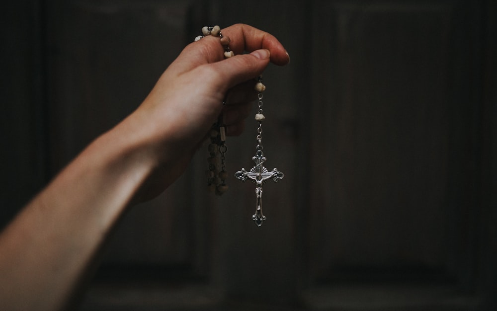 person holding silver beaded necklace