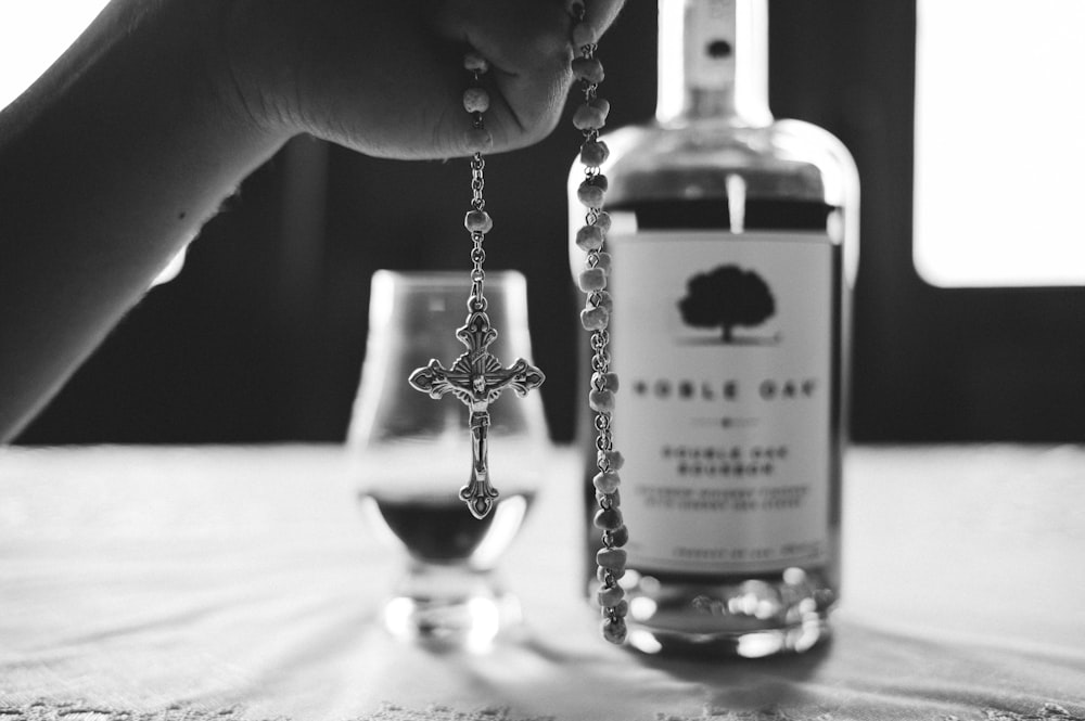 grayscale photo of person holding glass bottle