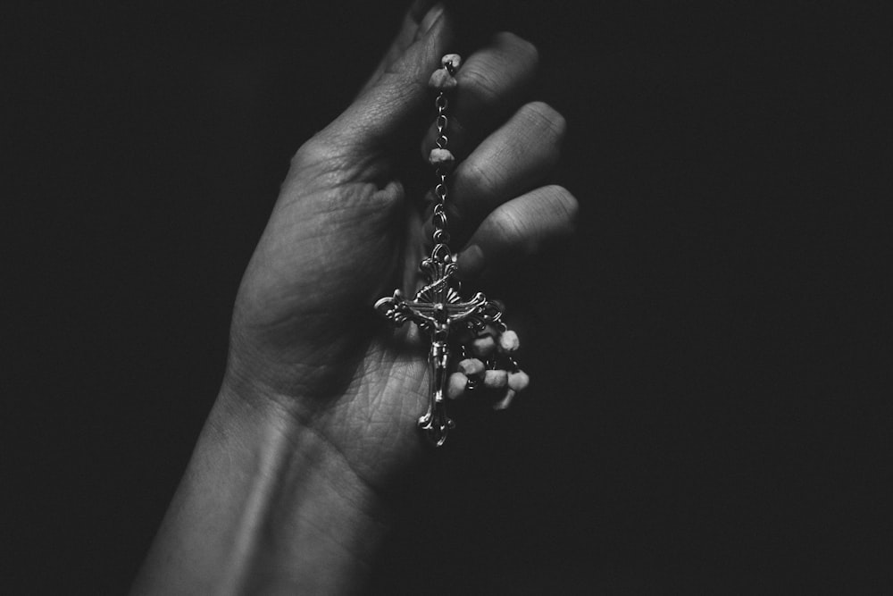 grayscale photo of person holding beaded accessory