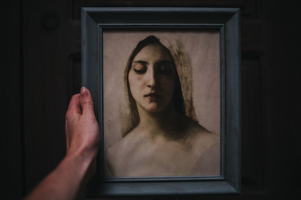 womans face painting with black wooden frame