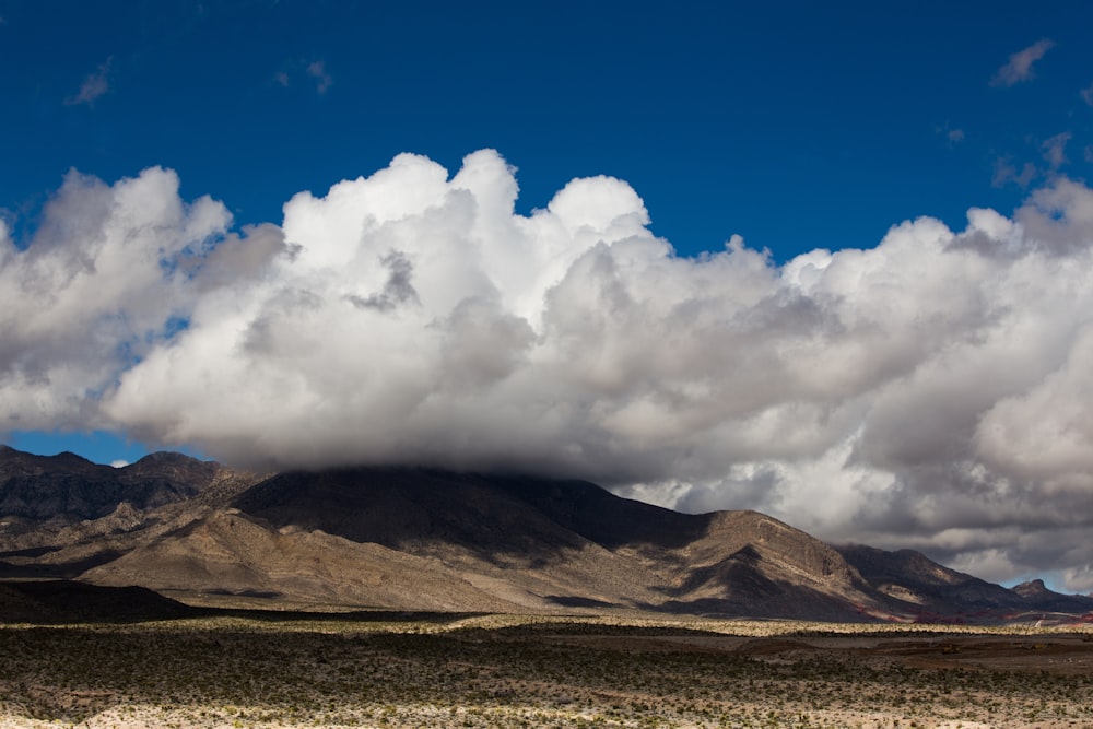 brown mountain under white clouds and blue sky during daytime