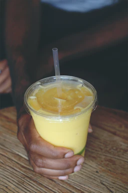 Close-up of a vibrant protein shake with fresh ingredients on a wooden table.