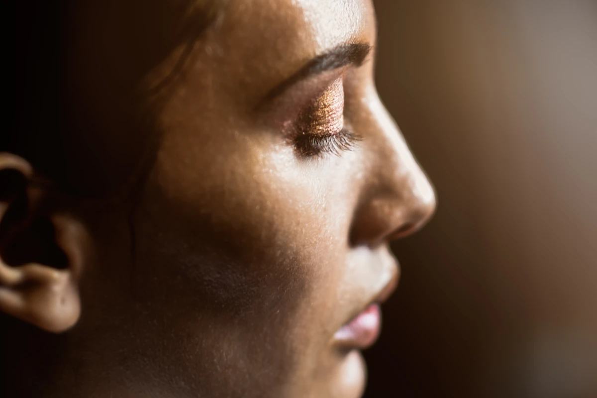 Perfil de rostro femenino con luz cálida que resalta el pómulo y la mandíbula