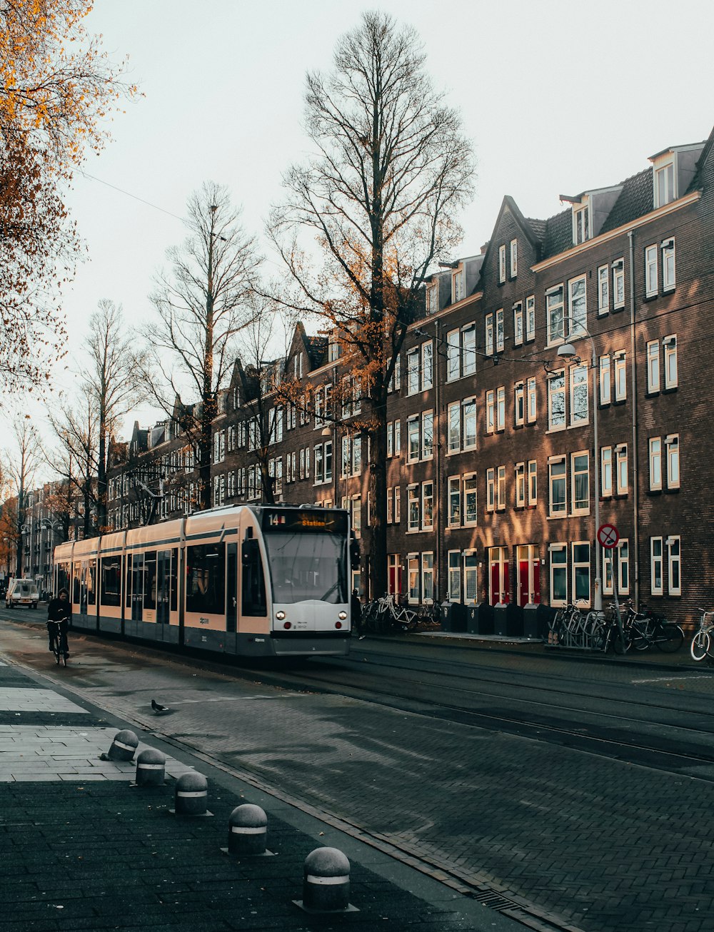 Weiße und gelbe Straßenbahn tagsüber auf der Straße in der Nähe des Brown Building