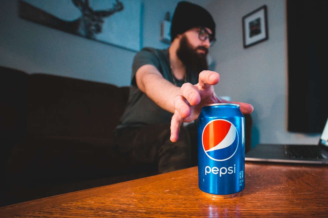 person holding pepsi can on brown wooden table