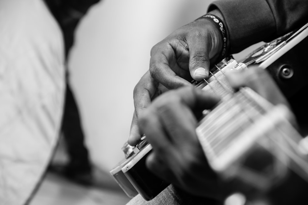 grayscale photo of man playing guitar