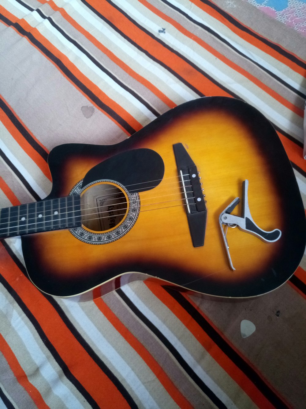 brown acoustic guitar on white and red striped textile