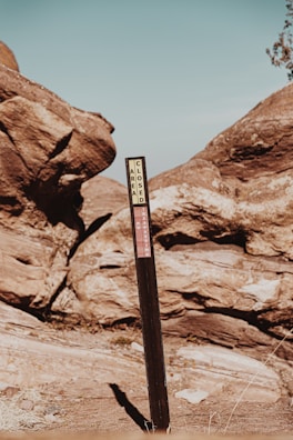 A weathered wooden signpost marking the edge of a dangerous zone, with bullet holes and scratches.