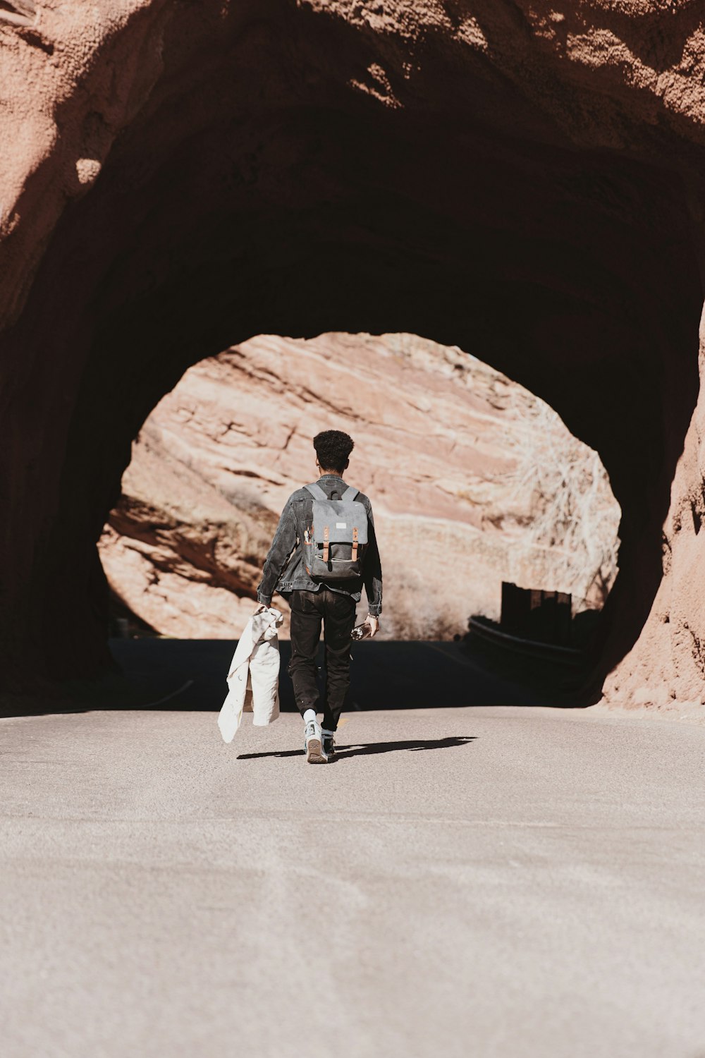 man in black jacket and white pants standing on brown rock formation during daytime