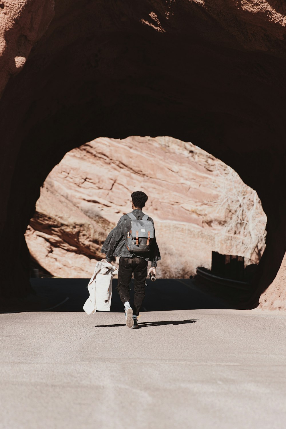 man in black jacket and white pants standing on road during daytime