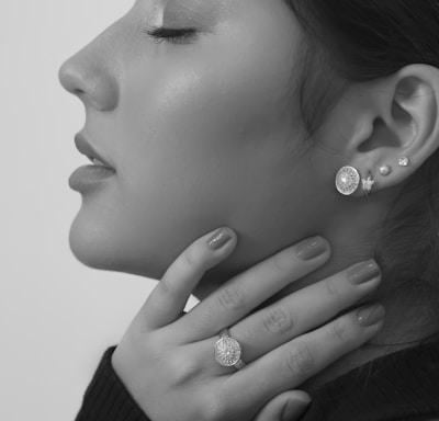 grayscale photo of woman wearing silver diamond stud earrings