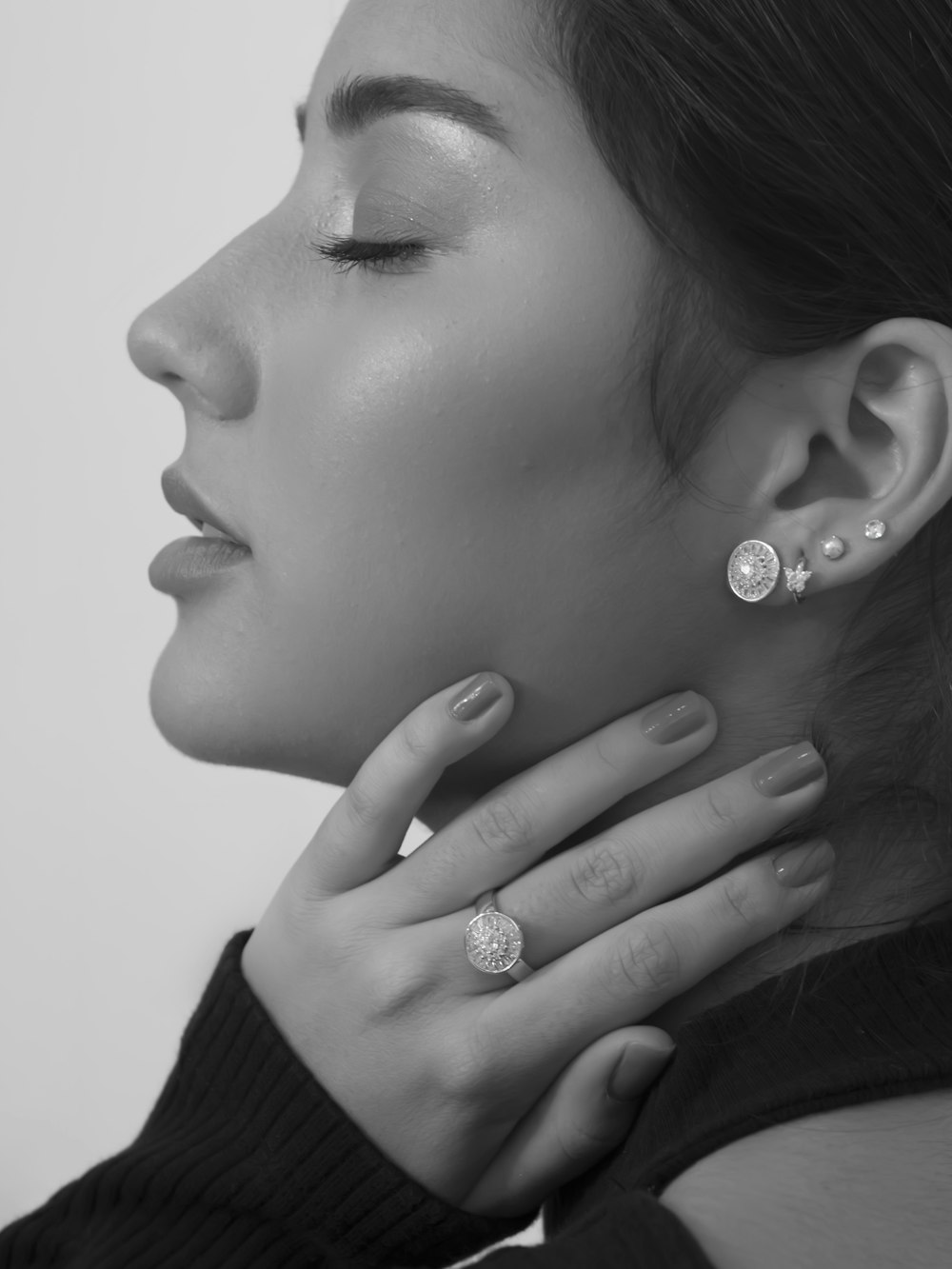 grayscale photo of woman wearing silver diamond stud earrings