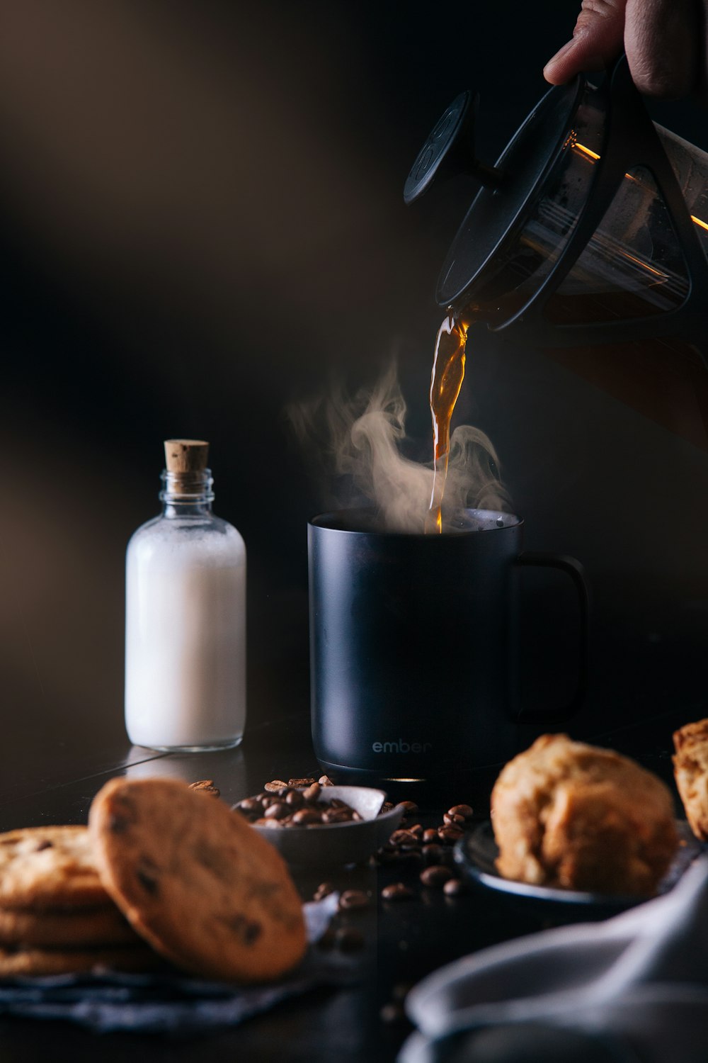 white glass bottle beside black ceramic mug