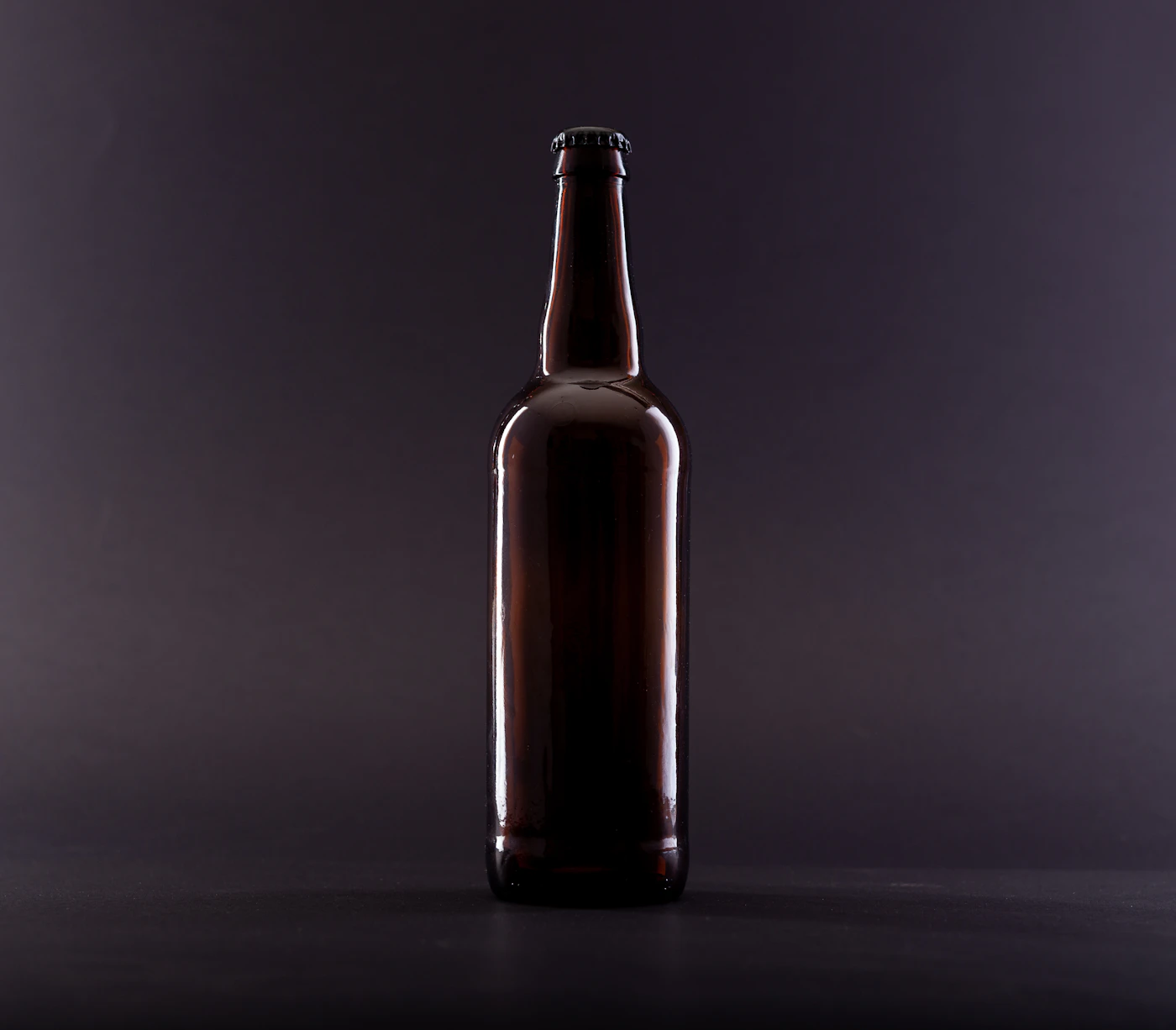Brown glass bottle on black surface — product identity work in context