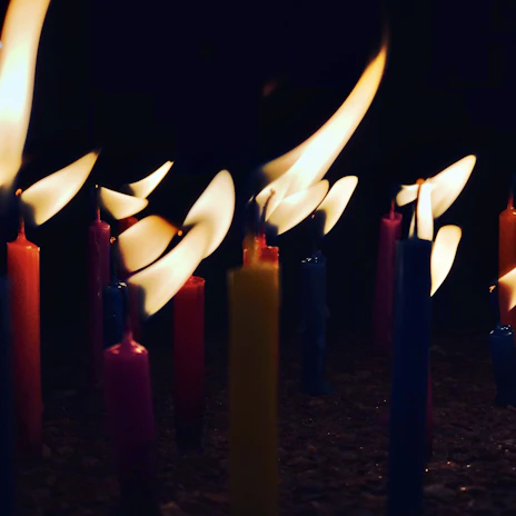 Close-up of colorful recycled crayon candles glowing warmly on a wooden table.