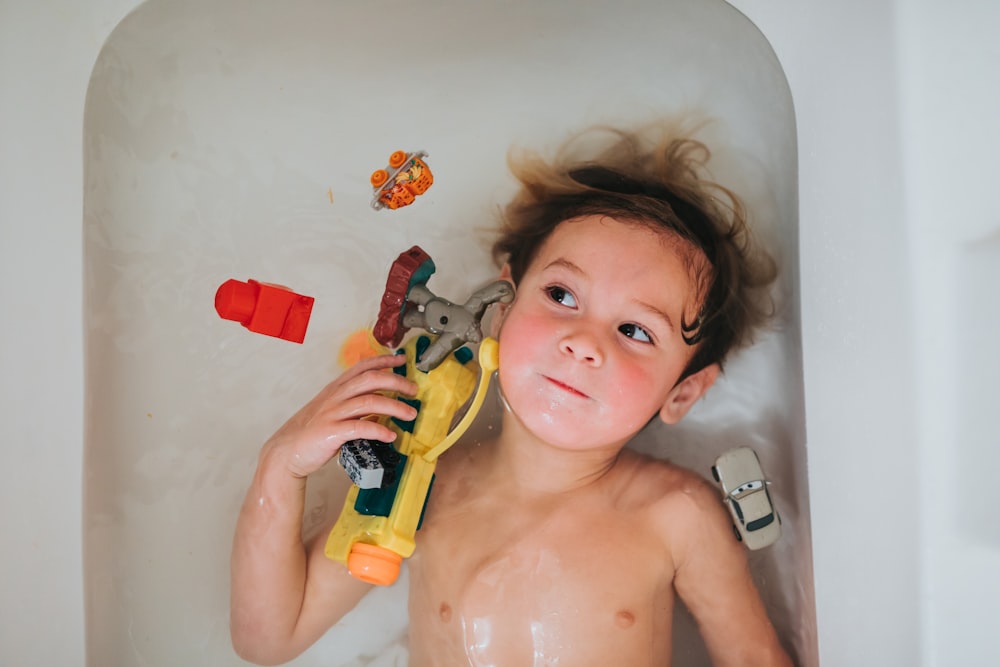 topless baby holding yellow and red plastic toy gun