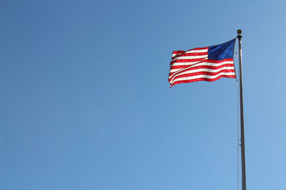 the american flag is flying high in the blue sky