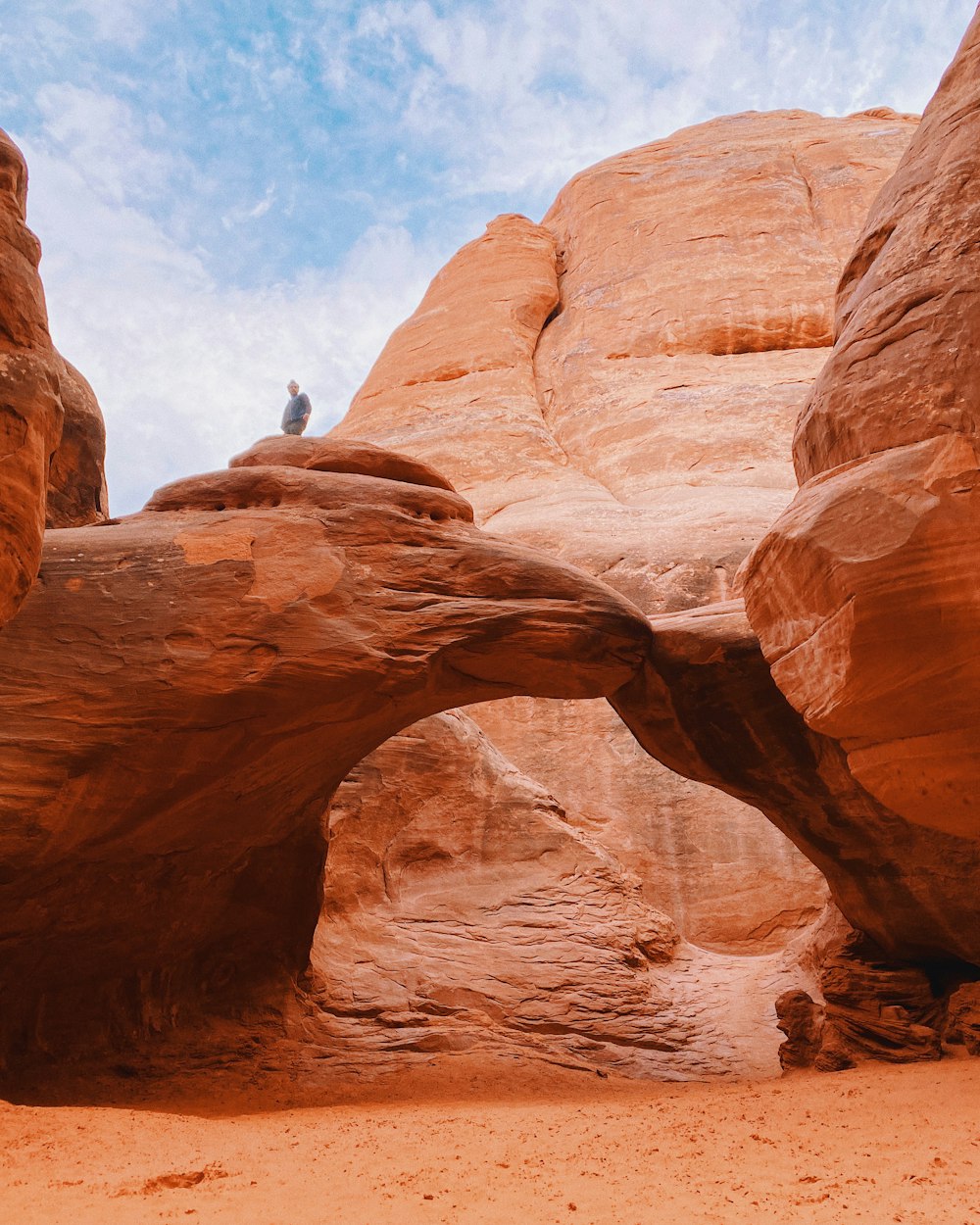 person climbing on brown rock formation during daytime